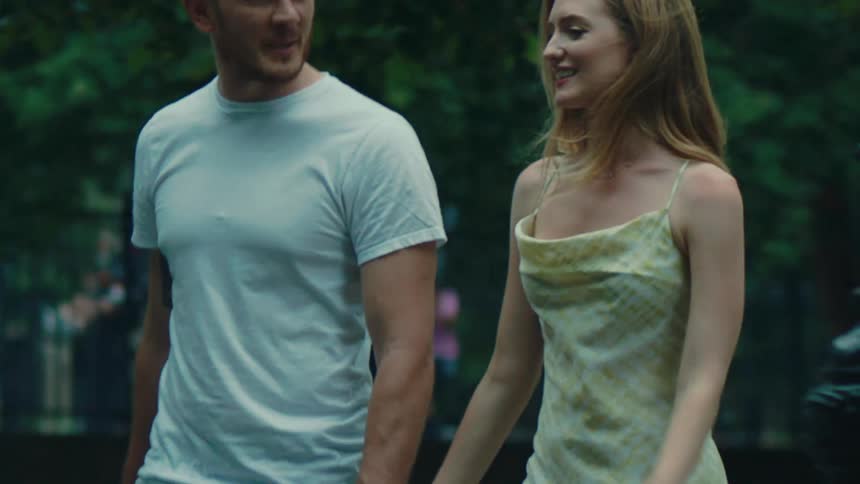 Man and woman holding hands walking through a park