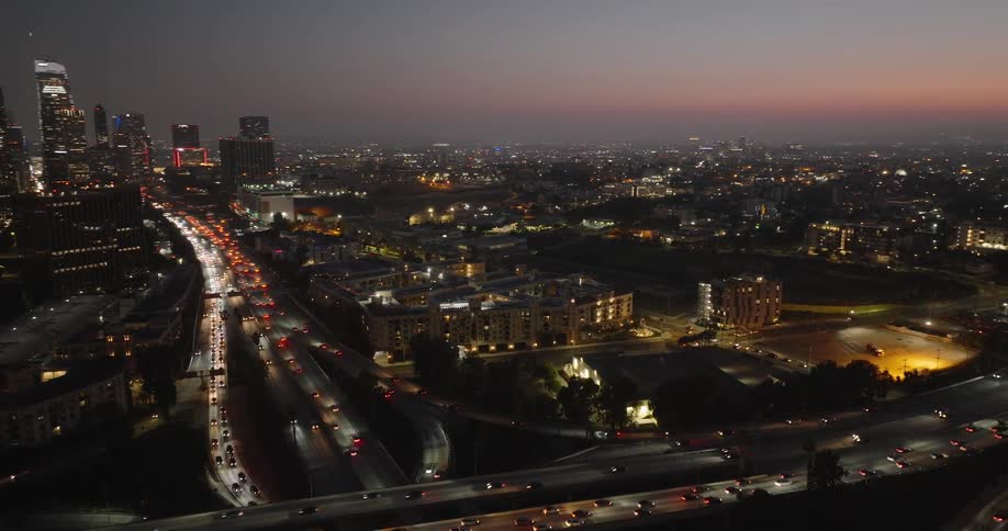 Aerial view of highways with vehicle traffic and a metropolis illuminated at night