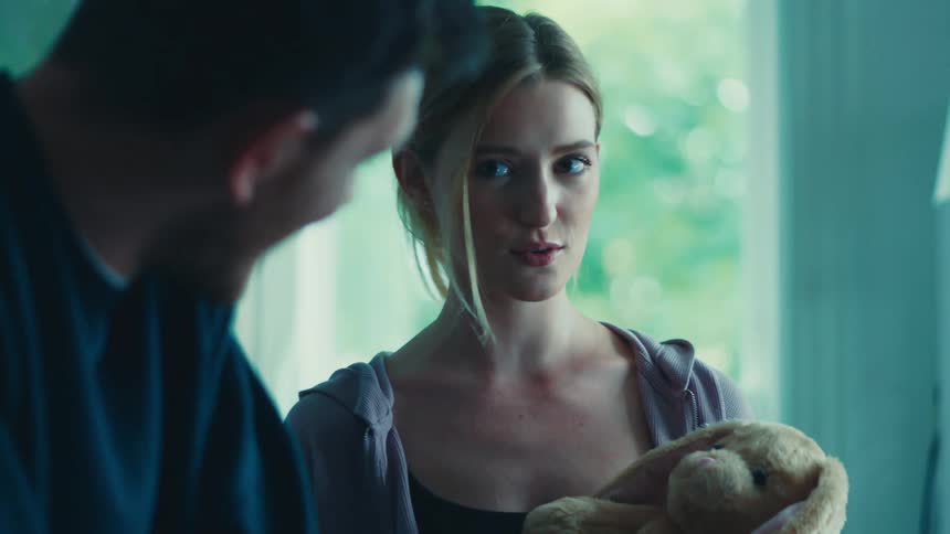 Couple smile while discussing a stuffed toy at home