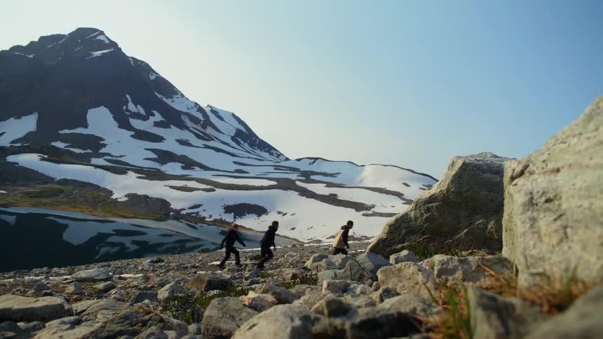 Three people walking through a valley in snowy mountainous