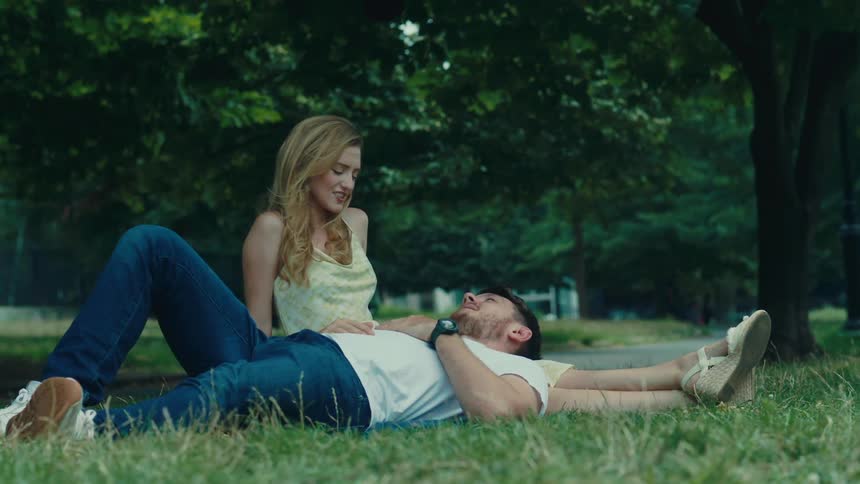 Man lying on the legs of a woman who is sitting on the grass