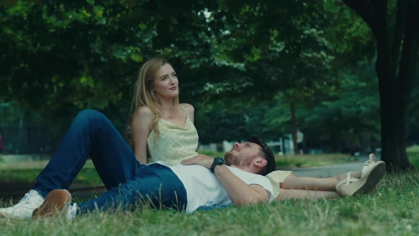 Woman sitting on the grass and a man lying on her lap