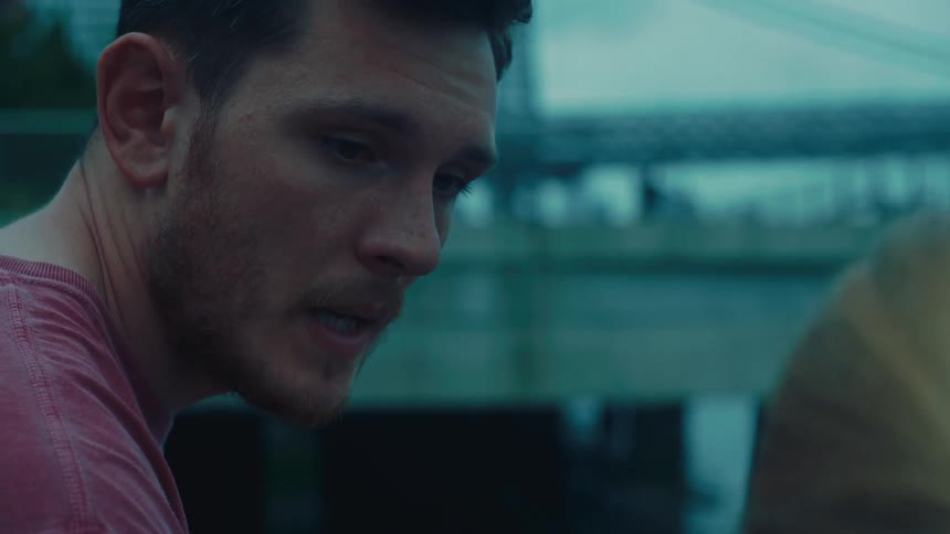 Man sitting near a bridge and talking to someone