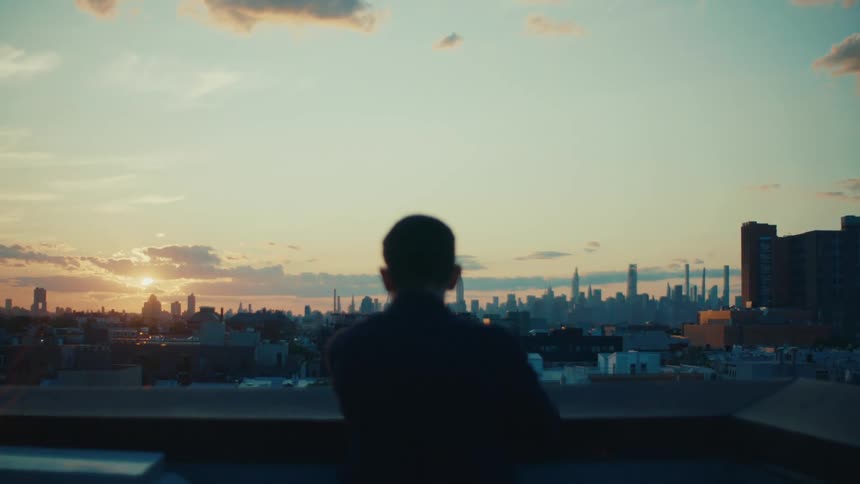 Man with his back turned on the balcony enjoying a panoramic view of a metropolis