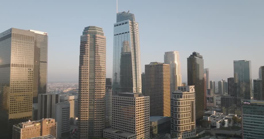 The los angeles skyline with several tall skyscrapers illuminated by the morning sun