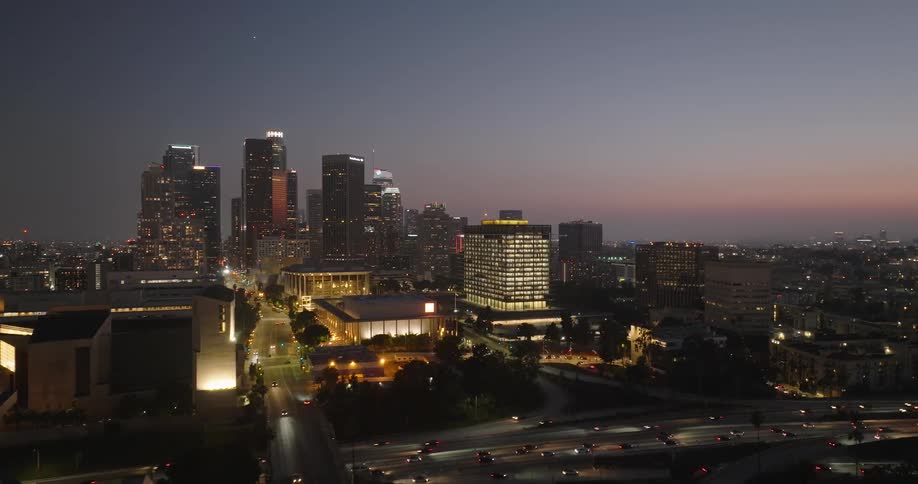 The los angeles skyline illuminated at night with the iconic skyscrapers standing tall against the twilight sky