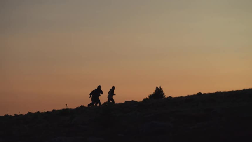 A trio of people run up a slope