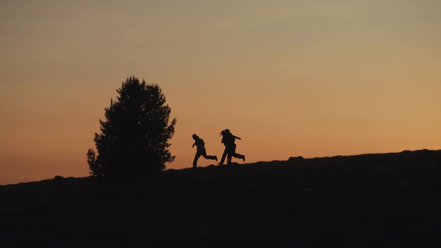Silhouette of three people walking on a mountain