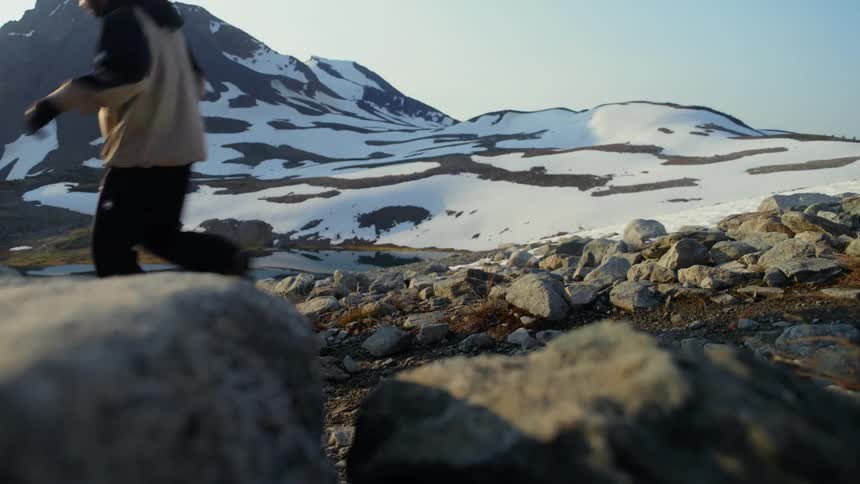 Legs of a person walking in a natural area with snowy mountains