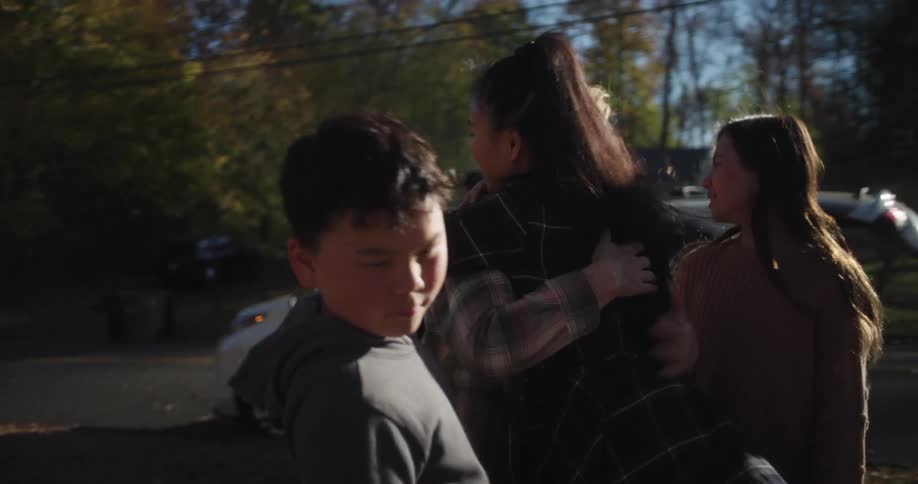 A family meeting in the front yard hugging each other on a cold autumn morning