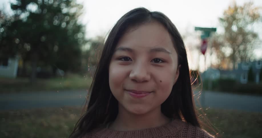 Portrait of a happy little girl in a backyard with a residential neighborhood in the background