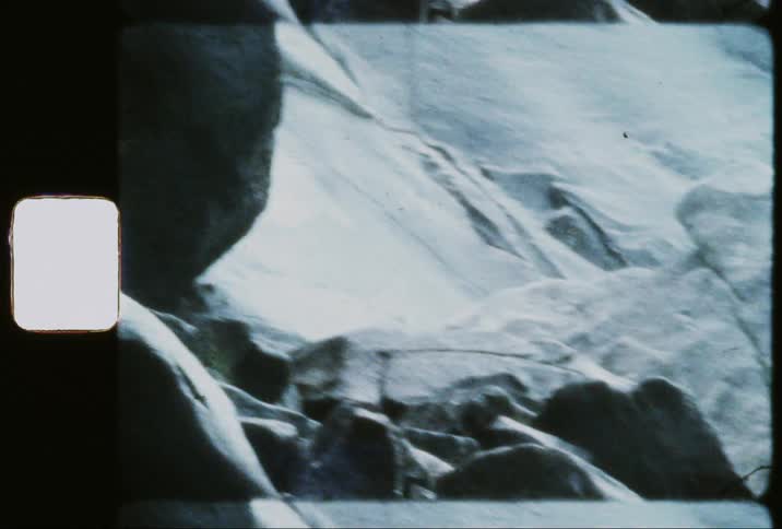 Female climbing on rocks beneath a waterfall formation