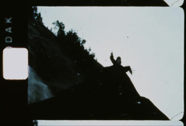 Two people on a rock next to a waterfall