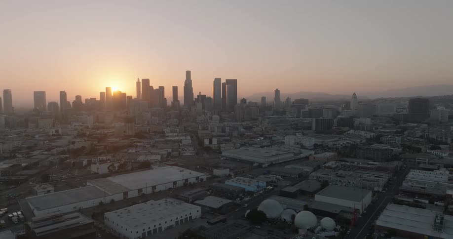 Aerial view of the los angeles skyline silhouetted against a vibrant sunset sky