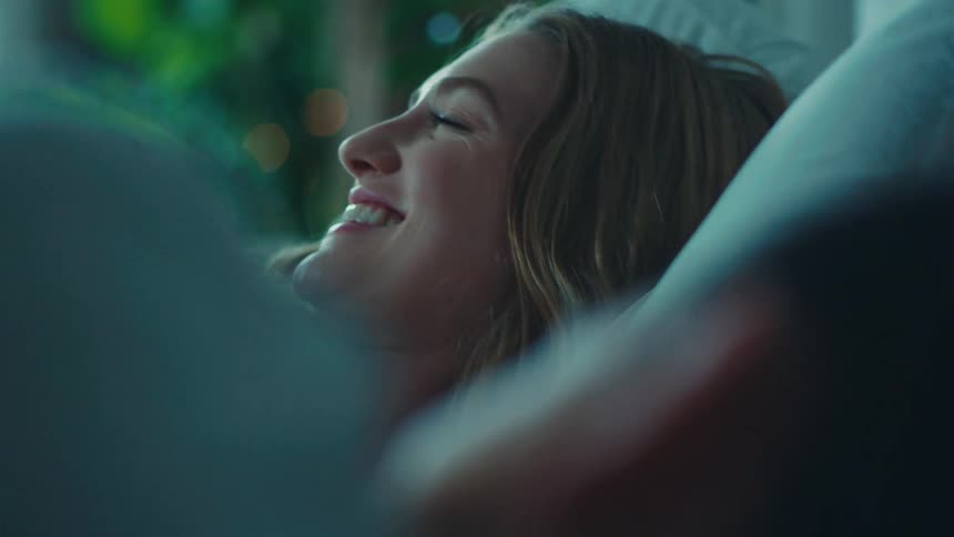 Blonde woman smiling while lying in bed with another person