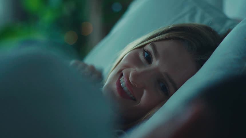 Woman lying happily next to a man in bed