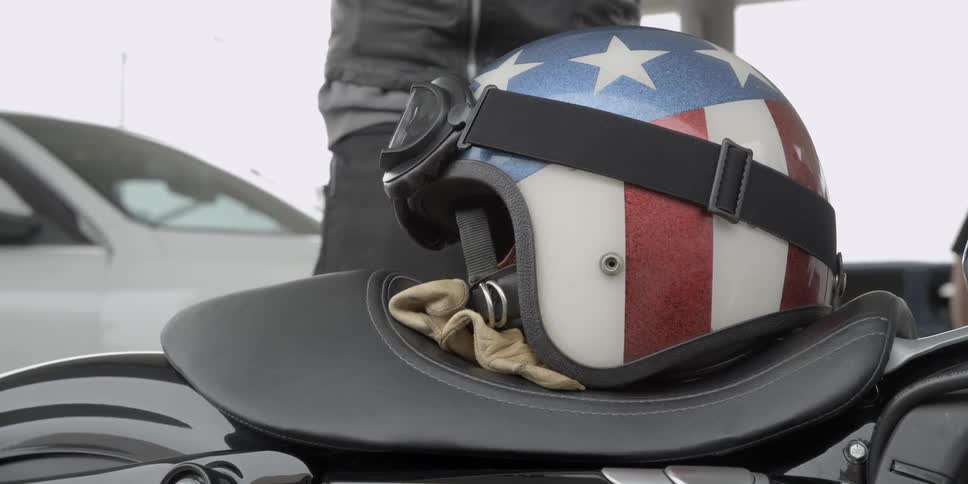 A helmet with an american flag sits on a motorcycle seat