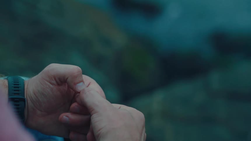 Hands of a person in the foreground and rocks and the sea in the background