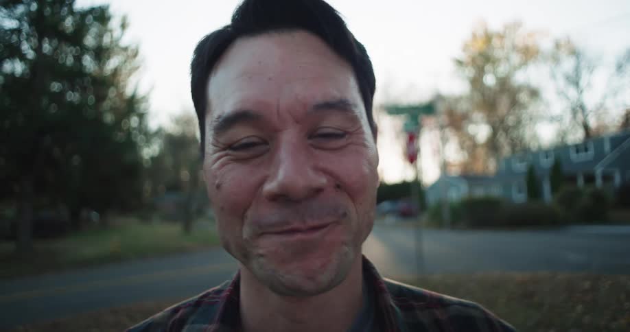 Man walks forward to smile while standing in a yard in a residential area during an autumn day