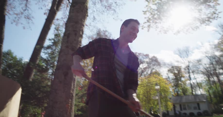 Man rakes leaves while a woman and a teenage boy kick at them