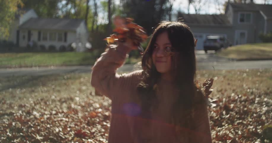 Boy and girl playing in a backyard with fallen leaves on the grass