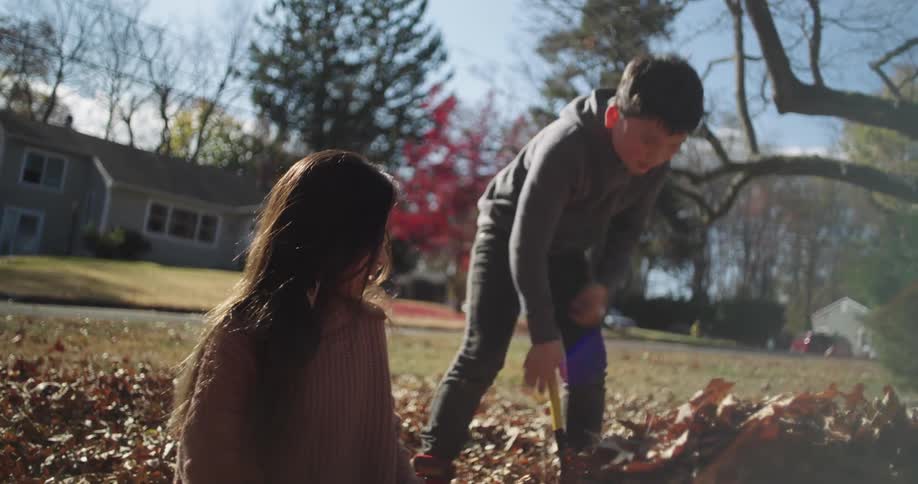 Father throwing dry leaves at his daughter in the backyard