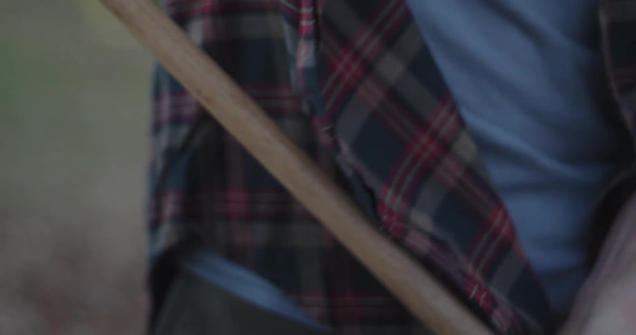 Close up of a persons hands and arms holding a wooden handle and cleaning an outdoor area