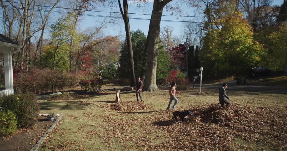 Family and a dog with two children running in the garden and playing in dry leaves