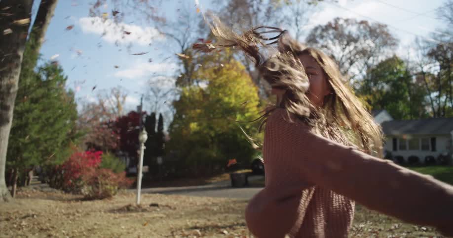 Girl playing with dry leaves in a backyard