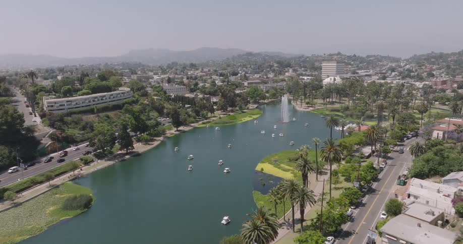 An aerial view of echo park lake in los angeles with its iconic swan boats and surrounding palm trees nestled amidst a residential neighborhood