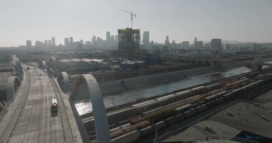 The 6th street viaduct under construction in los angeles with the city skyline in the background