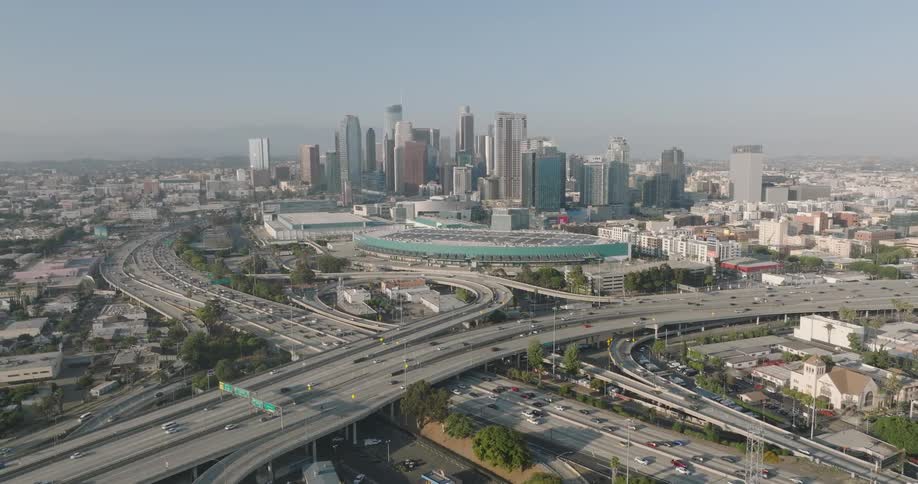 An aerial view of the los angeles skyline with the iconic skyscrapers and a complex network of highways