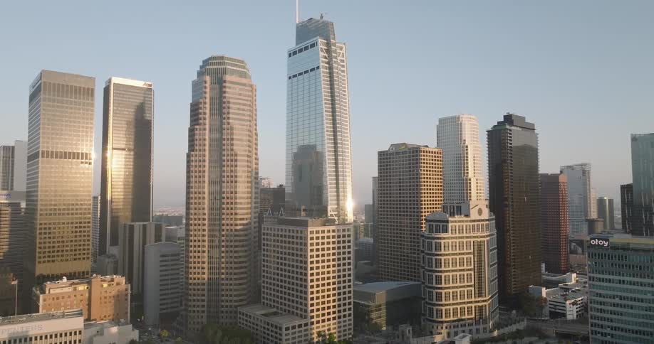 The los angeles skyline with several tall skyscrapers illuminated by the morning sun