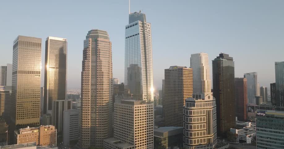 The los angeles skyline with several tall skyscrapers illuminated by the morning sun