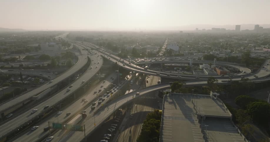 A complex highway interchange in los angeles with heavy traffic and a hazy atmosphere
