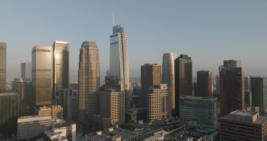 The los angeles skyline with several tall skyscrapers illuminated by the morning sun