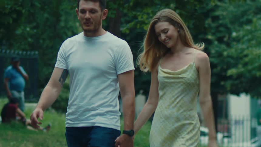 Woman and a man holding hands talking happily and walking together in an outdoor setting in a square