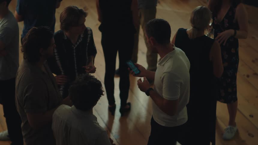 Group of people in an indoor space talking with a man receiving a call and leaving