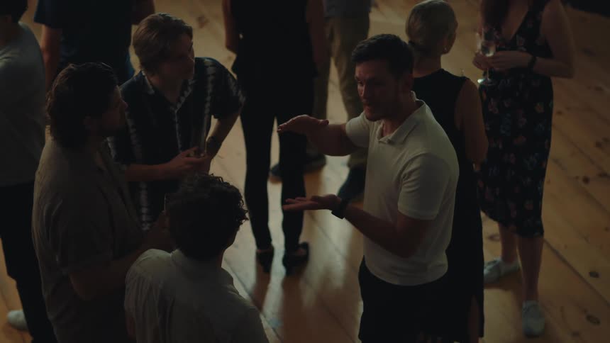 Group of people including men and women in an indoor space talking