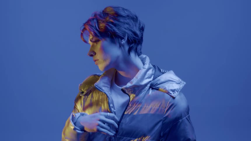 Woman in a jacket in an indoor space against a blue background