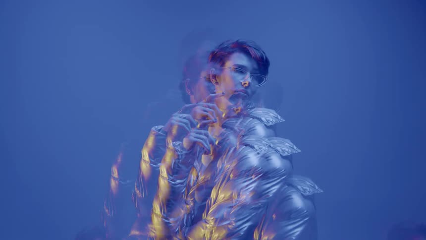 Multiple exposures of a woman in a silver jacket against a blue background