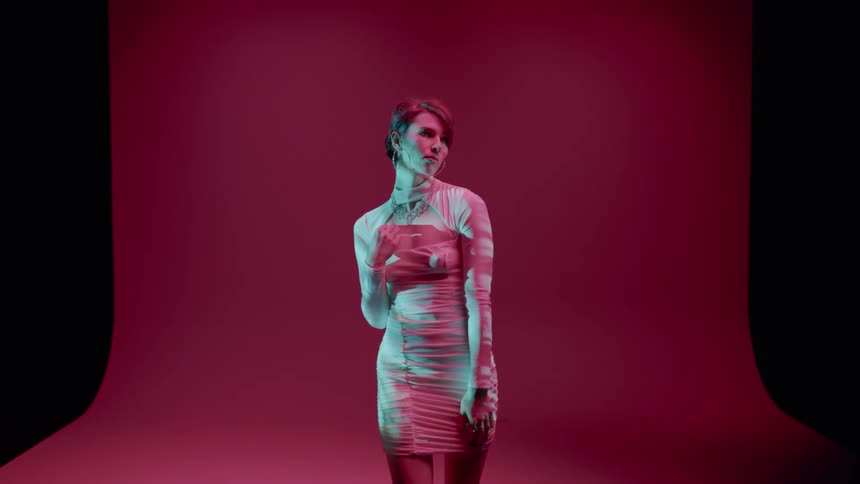 Woman in a long dress in an indoor space modeling with a reddish cloth in the background