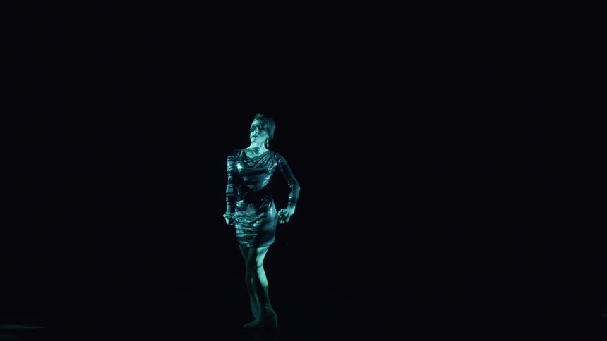 Woman in dress performing in a dark room with light reflection