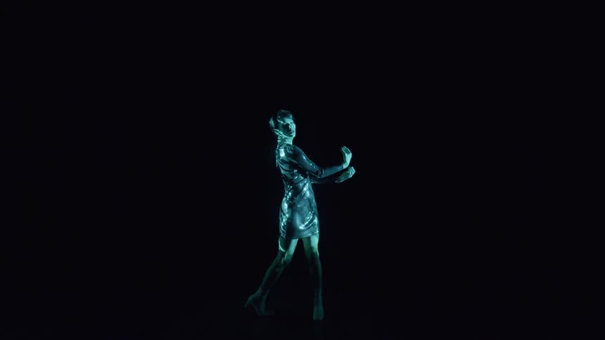 Woman in dress with lights focused on her in a dark environment
