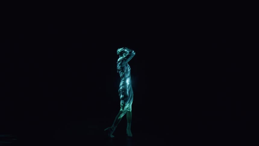 Woman in a shiny dress being lit in a dark room