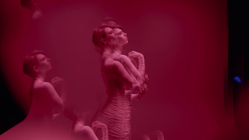 Multiple exposures of a woman in a fashionable dress performing against a red cloth background