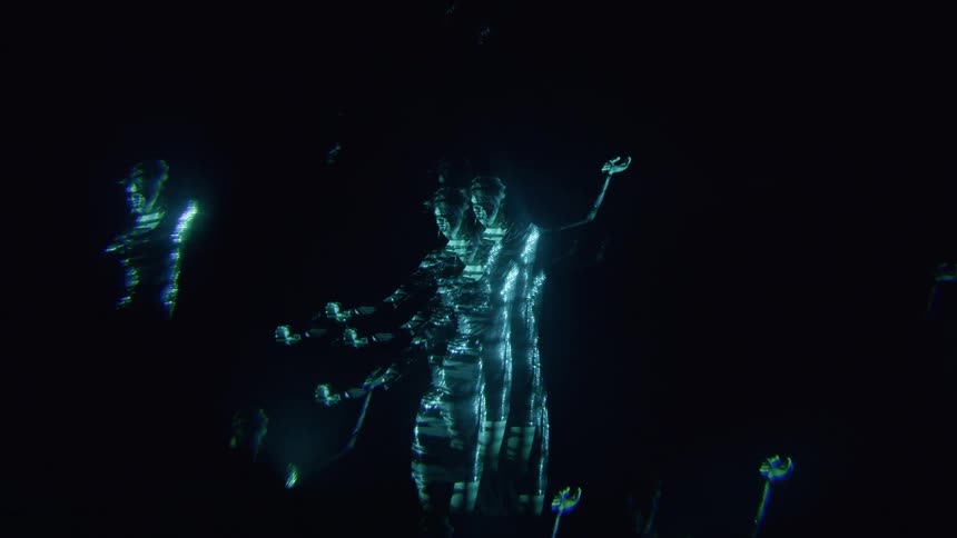Woman performing in a luminous dress in a dark indoor environment