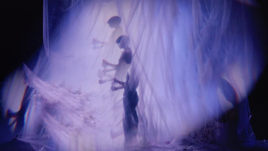 Person dancing alone behind a curtain with flashing lights