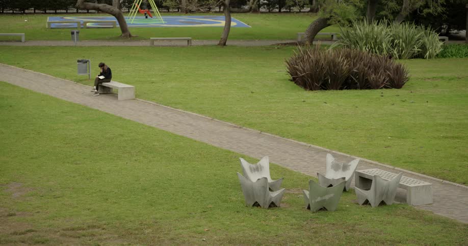 Woman sitting alone on a concrete bench in the middle of an empty park