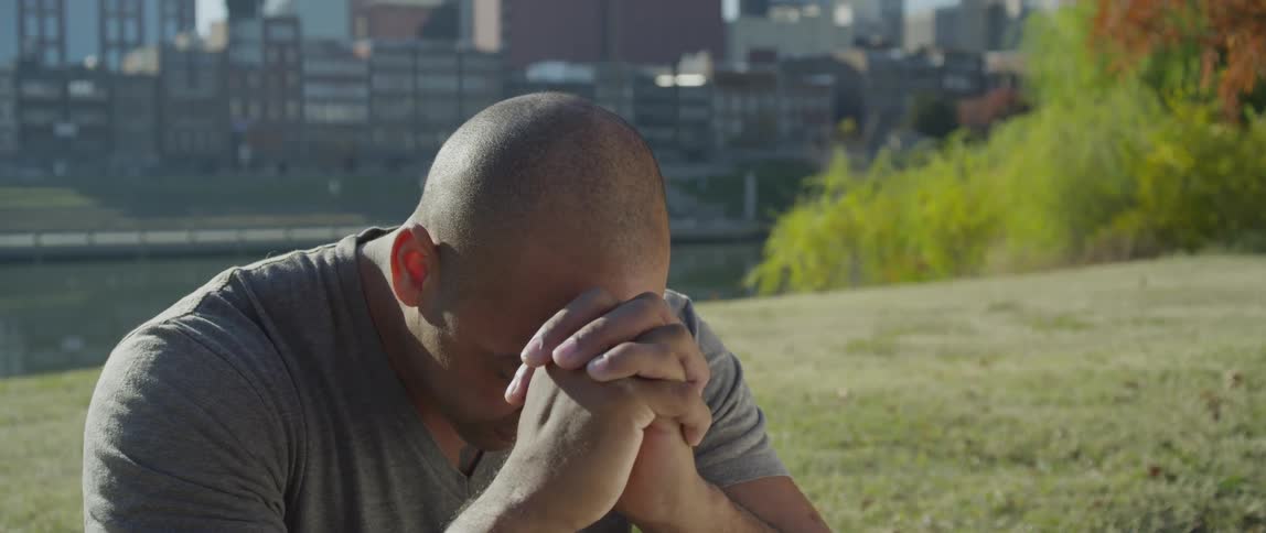 A man rests his head on his hands in a city park